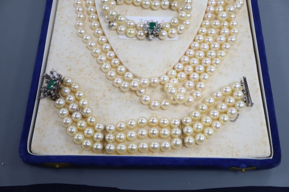 A triple strand cultured pearl necklace and matching bracelet with white metal, emerald and diamond set clasps & 1 other bracelet.